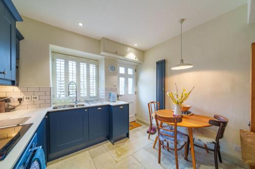 a kitchen with blue cabinets and a wooden table at Castlehaw View in Sedbergh