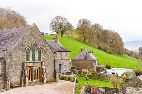 an old stone church with a green hill in the background at Castlehaw View in Sedbergh