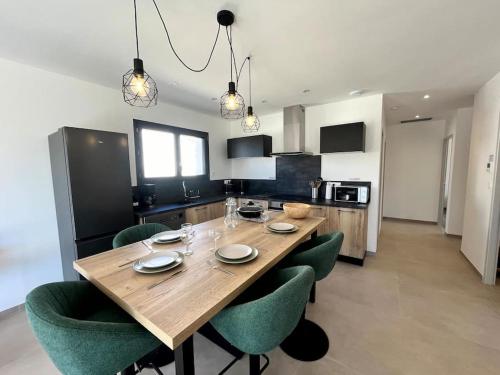 a kitchen with a wooden table and green chairs at Villa L'Olivier in Vallon-Pont-dʼArc