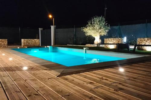 a swimming pool at night with a wooden deck at Villa L'Olivier in Vallon-Pont-dʼArc