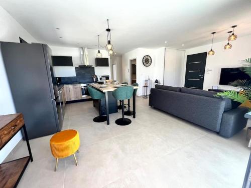 a living room and kitchen with a couch and a table at Villa L'Olivier in Vallon-Pont-dʼArc