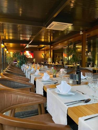 a row of tables in a restaurant with white table linen at Swiss Plus Hotel in Bihać