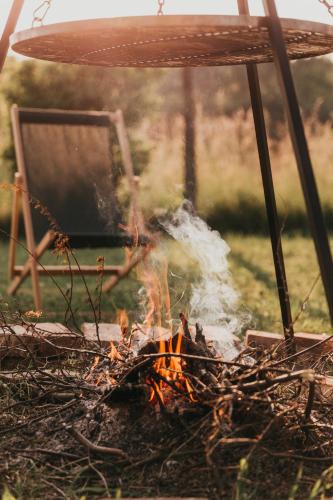 a fire in front of a chair and a chair at Śliwkowy Sad-Plum Orchard-Jura in Mirów