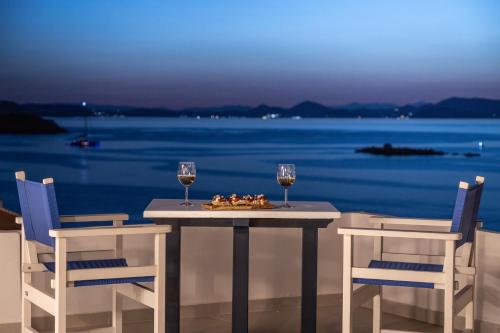 a table with two glasses of wine and a plate of food at Captain Hook in Hydra