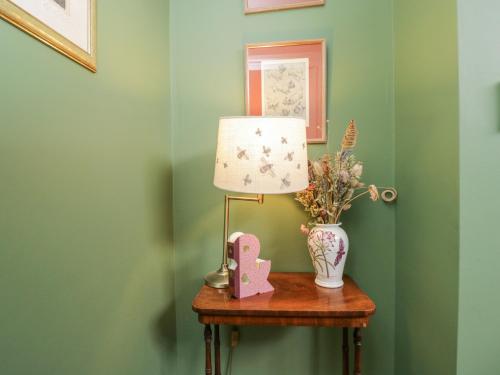 a table with a lamp and a vase on it at The Old Byre in Salisbury