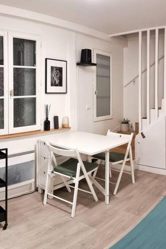une salle à manger blanche avec une table et des chaises blanches dans l'établissement Duplex Paris, à Paris