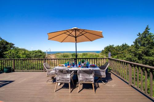 a table and chairs with an umbrella on a deck at Unique waterfront home with stunning views in Wellfleet