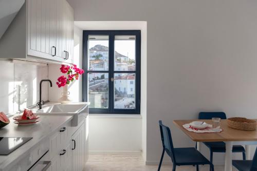 a white kitchen with a table and a window at Captain Hook in Hydra