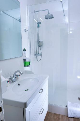 a white bathroom with a sink and a shower at The Originals City, Hôtel Armen Le Triton, Roscoff in Roscoff