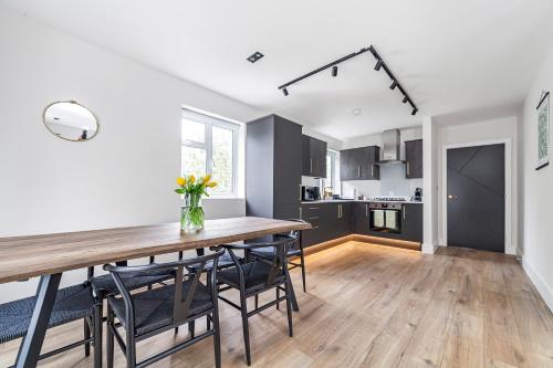 a kitchen and dining room with a wooden table and chairs at Arte Stays - Serviced Apartments for Leisure and Business - Private Parking - 12 minutes walking from Wembley Stadium in London