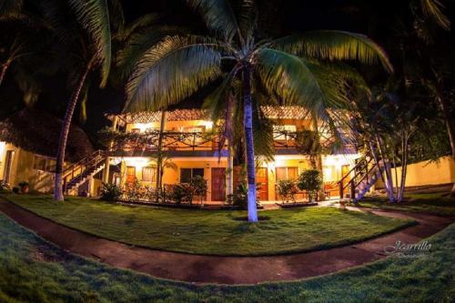 a building with palm trees in front of it at Hotel Cafe del Sol in Monterrico