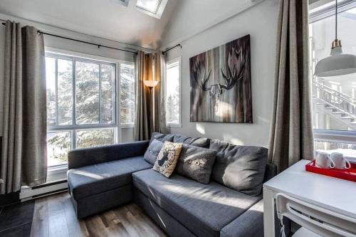 a living room with a blue couch and windows at Modern Chalet in the Mont Tremblant Ski Village in Mont-Tremblant