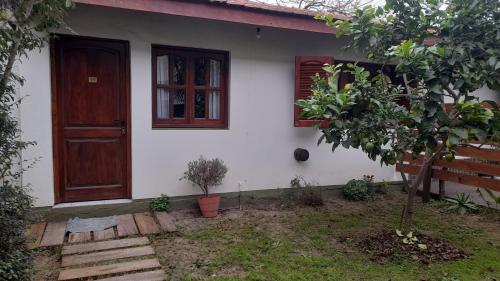 Casa blanca con puerta de madera y árbol en DelMar, en San Clemente del Tuyú