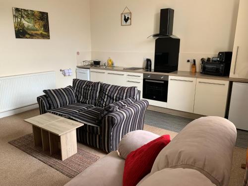 a living room with two couches and a kitchen at Charlotte Street 2 Bedroom Apartment in Ayr