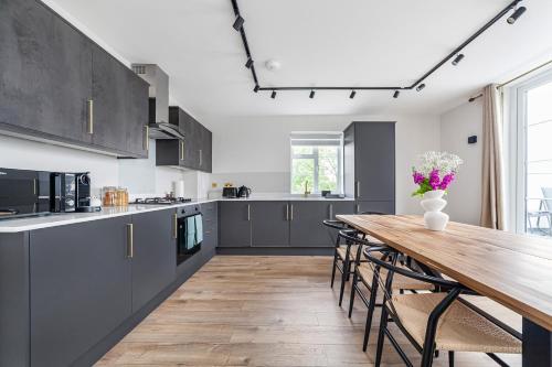 a kitchen with a wooden table and a wooden floor at Arte Stays - Serviced Apartments for Leisure and Business - Private Parking - 12 minutes walking from Wembley Stadium in London