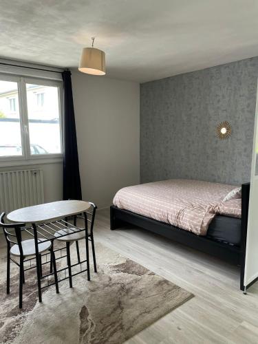 - une chambre avec un lit, une table et une chaise dans l'établissement Apparemment Rennes, à Saint-Jacques-de-la-Lande