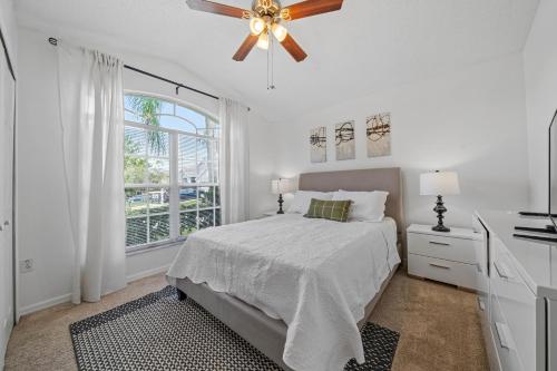 a white bedroom with a bed and a ceiling fan at Stunning 4-bedroom Villa w/ Pool - Close to Disney Parks and Gulf Courses! in Davenport