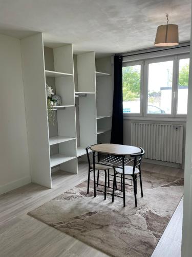 une table et des chaises dans une pièce avec une fenêtre dans l'établissement Apparemment Rennes, à Saint-Jacques-de-la-Lande