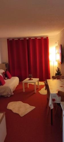 Cette chambre dispose de rideaux rouges, d'un lit et d'une table. dans l'établissement Studio montagne 4 pers, au Corbier