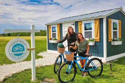 two women standing next to a bike in front of a tiny house at Bunkies-The Commissioner in Ottawa