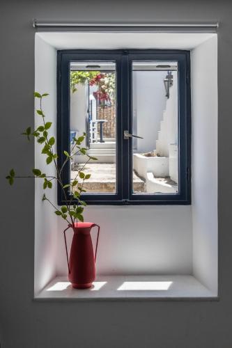 a red vase sitting on a window sill with a plant at Captain Hook in Hydra
