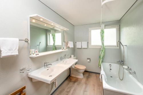 a bathroom with a sink and a tub and a toilet at CPM Apartments in Grindelwald
