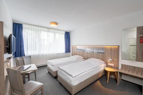 a hotel room with two beds and a desk at Hotel & Gästehaus Rostock Lütten Klein in Rostock
