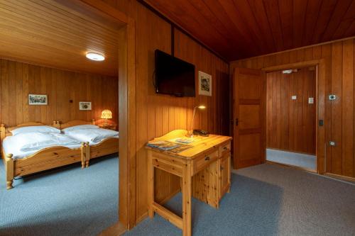 a bedroom with a bed and a desk with a television at CPM Apartments in Grindelwald