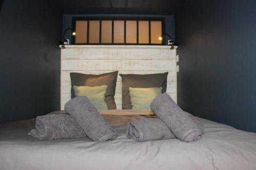 a bed with four pillows on top of it at Le Petit Moulin in Gradignan