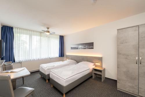 a hotel room with a bed and a desk and a bed at Hotel & Gästehaus Rostock Lütten Klein in Rostock