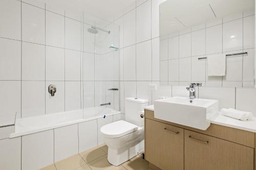 a white bathroom with a toilet and a sink at Quest Chermside on Playfield in Brisbane