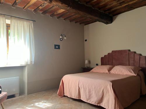 a bedroom with a bed with pink sheets and a window at La Torre wine resort in Montecarlo