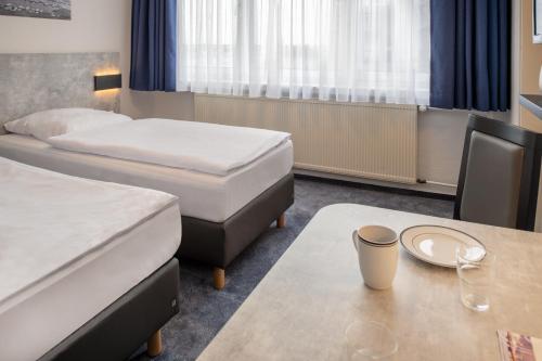 a hotel room with two beds and a table at Hotel & Gästehaus Rostock Lütten Klein in Rostock