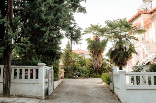 a white fence in front of a house with trees at Serenity Hill in Veria