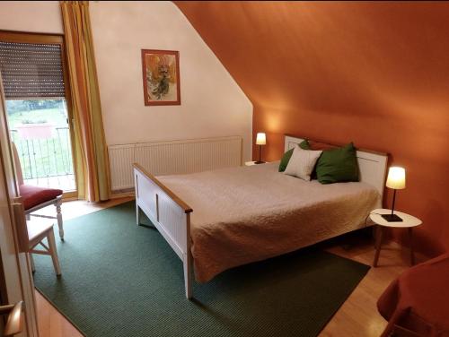a bedroom with a bed with green pillows and a window at Orangerie Zimmer Gehaichnishof 7born in Maring-Noviand