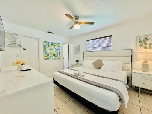a white bedroom with a bed and a ceiling fan at Sunrise Family Oasis Pool Lake Canal Views in Sunrise