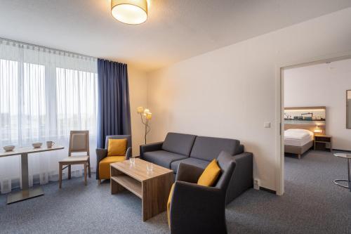 a hotel room with a couch and a bedroom at Hotel & Gästehaus Rostock Lütten Klein in Rostock