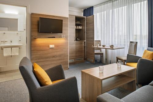 a hotel room with chairs and a tv and a table at Hotel & Gästehaus Rostock Lütten Klein in Rostock