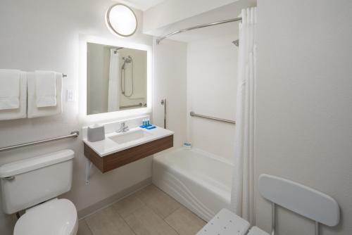 a white bathroom with a sink and a shower at Holiday Inn Express & Suites Orlando International Airport by IHG in Orlando