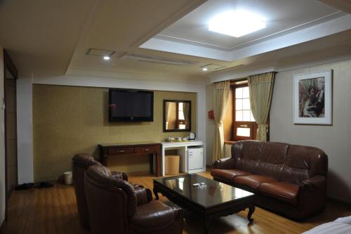 een woonkamer met lederen meubels en een flatscreen-tv bij Palace Hotel Gwangju in Gwangju