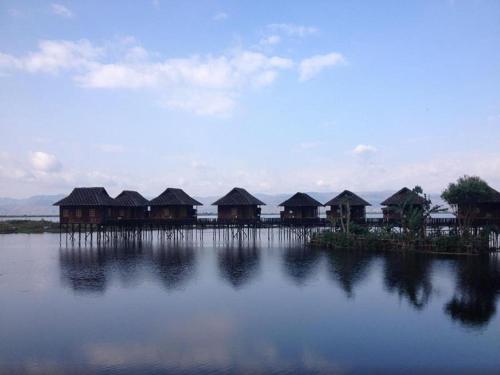 a row of huts on the water with at Golden Island Cottages Thale U Hotel in Ywama
