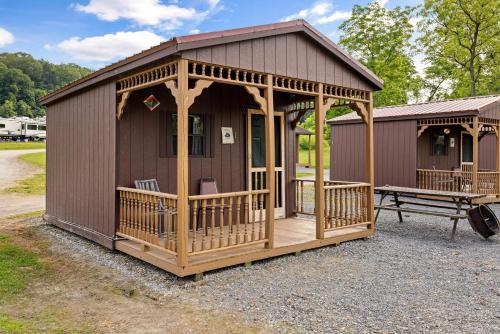 een kleine hut met een veranda en een bank bij Cozy Cabin3 Within Campground in Mifflinburg