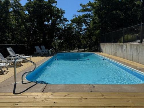 a swimming pool with blue water and chairs and trees at Sunset Beach Resort in Osage Beach