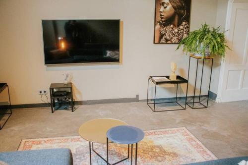 a living room with two tables and a flat screen tv at Boutique 2br Apt With Garden At Fontys in Tilburg