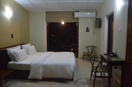 a bedroom with a bed and a desk and a window at The Buena Vista Kandy in Kandy
