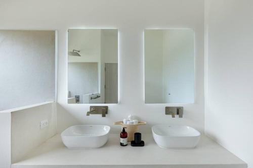 a white bathroom with two sinks and a mirror at Elegant Ocean View Villa Serena in Cóbano