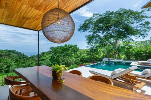 a dining room with a table and chairs and a pool at Elegant Ocean View Villa Serena in Cóbano