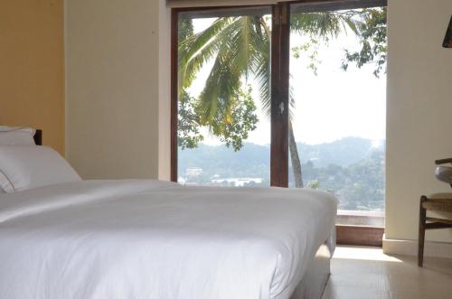 a bedroom with a white bed and a large window at The Buena Vista Kandy in Kandy