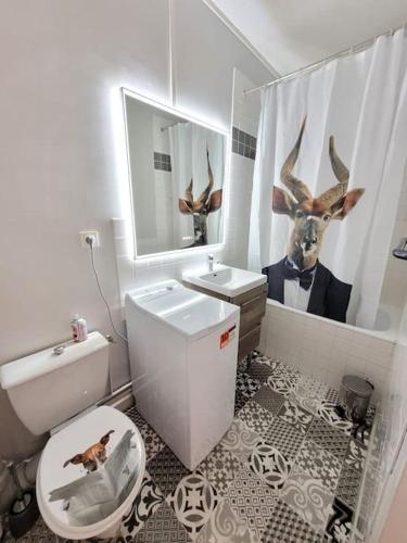 une salle de bain avec des toilettes et une tête de cerf sur le rideau de douche dans l'établissement F1 hyper centre, à Clermont-Ferrand
