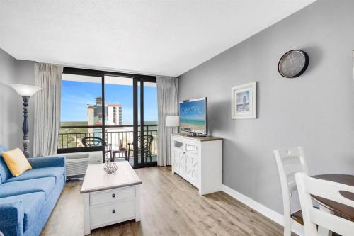 a living room with a blue couch and a large window at 1BR Oceanview Suite Relaxation Awaits Dogs OK! 1704 in Myrtle Beach